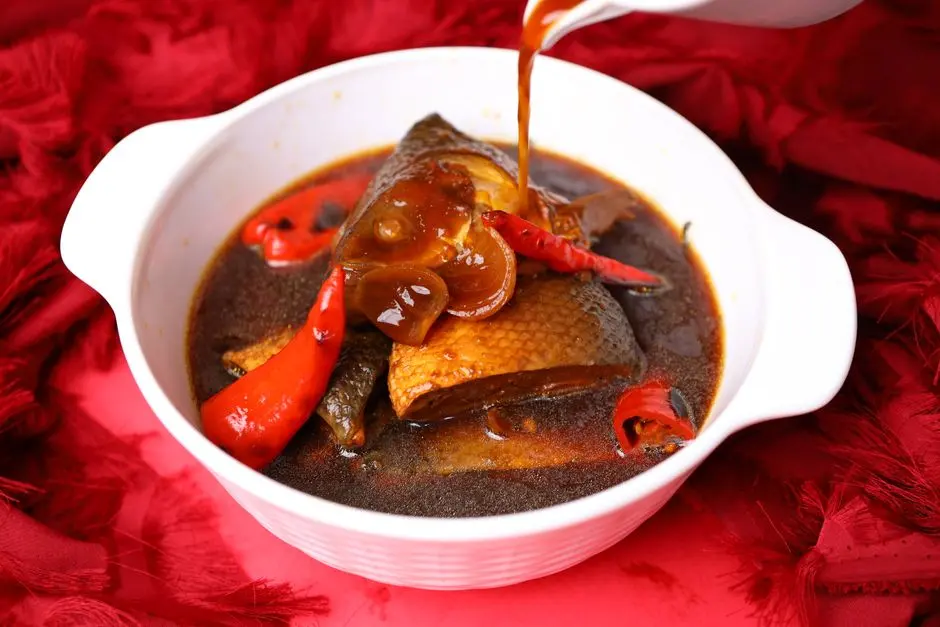 Ikan kuah kuning Tobelo dalam mangkuk keramik putih dengan nasi putih dan sambal di samping